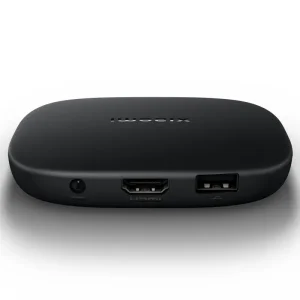 Compact Xiaomi TV Box S (3rd Gen) next to a TV displaying the Google TV interface.